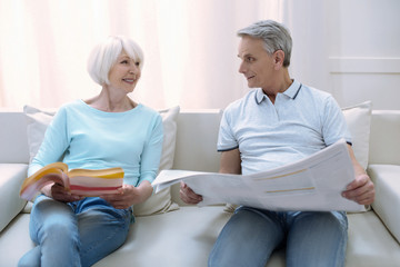 Nice readers. Cheerful friendly old people sitting on a comfortable sofa together and reading