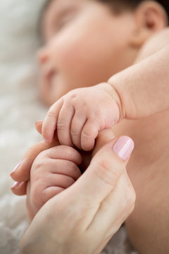 Sleeping baby holding mom's finger