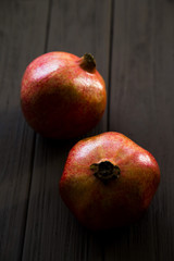Fototapeta na wymiar two pomegranates on a wooden table. dark background