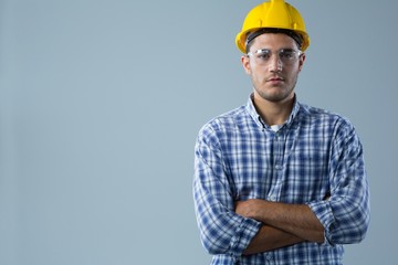 Male architect standing with arms crossed against white