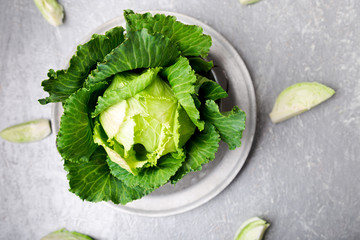 Fresh green cabbage in metal plate on grey background. Top view. Copy space.