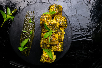 Grilled corn with sauce pesto on black slate plate. Top view. Vegan food.