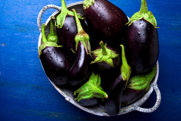 Fresh eggplant in grey basket on blue wooden table.Rustic background. Top view. Copy space. Vegan vegetable.