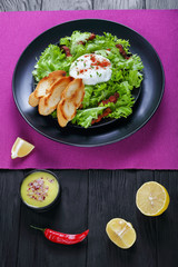 classic salad Lyonnaise on black plate