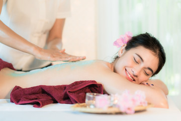Fototapeta na wymiar Young Asian woman receiving salt massage in spa salon, Hand putting salt scrub on female back, Spa concept