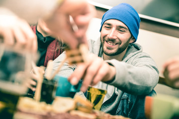 Happy guy with friends eating finger food and drinking beer at pub - Cheerful people having fun at...