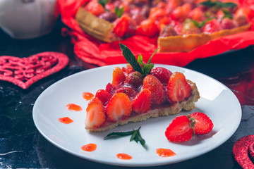 Strawberry pie on white plate black wooden table. One piece.  Romantic. Love. Heart. Toned photo. Valentine Day