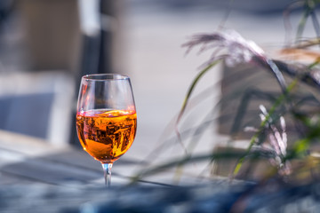A glass with an orange alcoholic beverage stands on a table in a lakeside restaurant in sunny weather