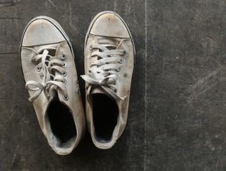 dirty and old white shoes on dirty cement ground