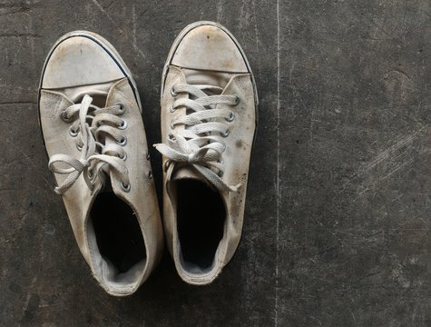 Dirty And Old White Shoes On Dirty Cement Ground