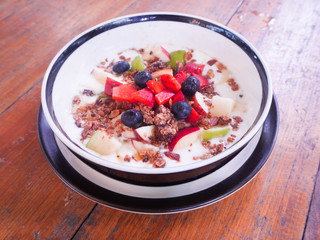 Closeup mixed fruit yoghurt in big bowl,on wooden desk,health food for diet.