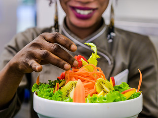 African lady chef plating salad in a restaurant
