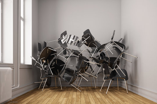 Kleiner Raum mit vielen Stühlen chaotisch gestapelt