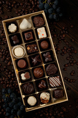 luxury box with tasty chocolate pralines on a table with grapes