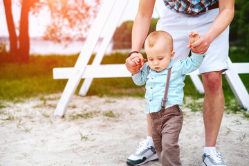 Fototapeta premium Happy young father with little son have fun and learning to walk outdoor in the park
