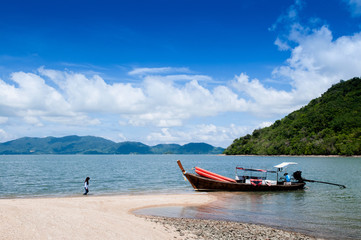 Rock sand beach on small island with local fisherman and boat near Koh Lanta
