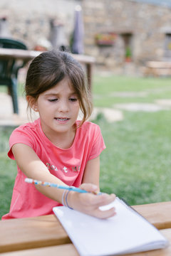 Girl looking puzzled while writing in notebook