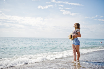 Fototapeta na wymiar Beautiful model relaxing on a beach of sea, wearing on jeans short, leopard shirt and hat.