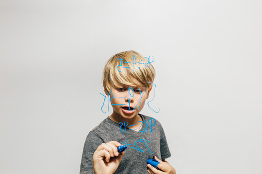 Boy writing equation onto glass wall