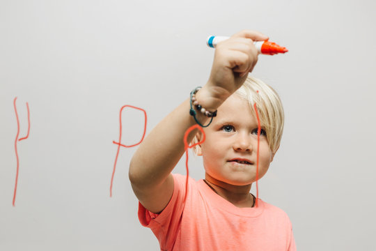 Boy writing reversed letter P onto glass wall