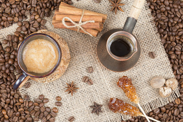 Obraz na płótnie Canvas Strong coffee with foam, cinnamon, sugar stick, nutmeg on the burlap