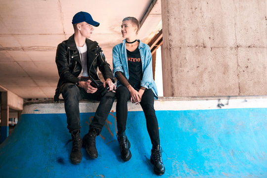Young skateboarding couple smoking and talking on skate ramp - Powered by Adobe