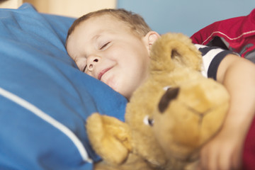 Child sleeping in his bed with teddy