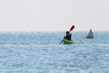 Silhouette of man in kayak on quiet sea under the midday summer sun. Sport Training