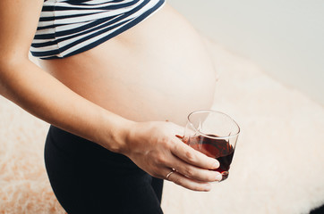 Pregnant girl with red pomegranate juice in hand