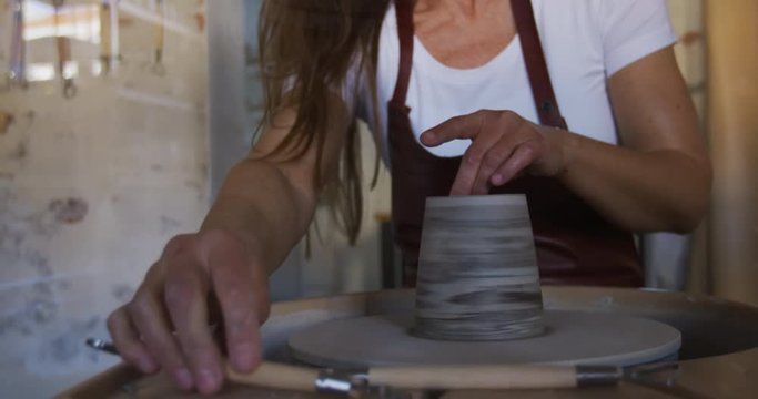 Woman turning a piece of clay in her pottery studio