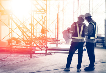 Silhouette engineer in safety protective equipment standing orders for construction crews to work...