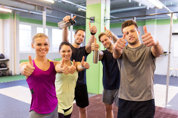 group of happy friends in gym showing thumbs up