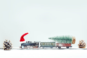 Xmas toy train in snow with xmas tree on board. Christmas, New Year travel concept.