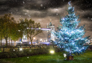 Weihnachtsbaum vor der Tower Bridge in London mit Schneefall bei Nacht