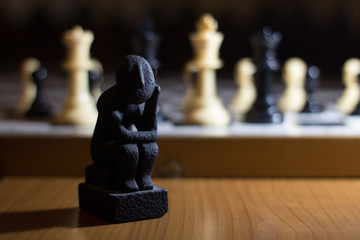 the thinker statue on a chess board coil small thinking about strategy