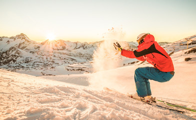 Skier playing with snow at sunset on top of the mountain