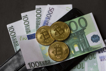 Golden bitcoins and banknotes Euro in my wallet on a black background. the new virtual money