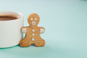 gingerbread man stands near a white mug, copy space