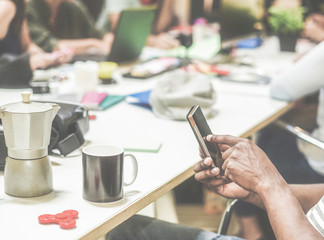 Black man using mobile phone during startup in creative office - Diverse culture people working together at new project - Technology, business and digital job concept