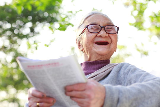 Senior asian woman reading book in the yard