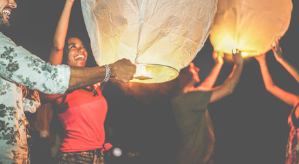 Happy friends lighting sky lantern on the beach in the night