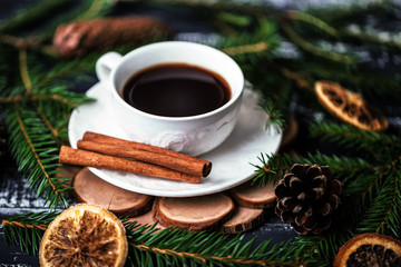 Obraz na płótnie Canvas A cup of coffee with cinnamon on dark wooden background. A cup of coffee in christmas decorations 