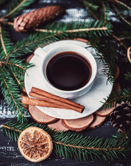 Obraz na płótnie Canvas A cup of coffee with cinnamon on dark wooden background. A cup of coffee in christmas decorations 