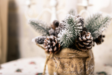 Winter holidays background of pine cones powdered with artificial snow and white downy shawl. Merry Christmas brown backdrop