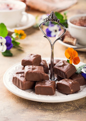 Soft nougat chocolate sweets on white plate with pansy flowers. Party food concept.