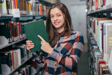 Young female girl  student smiling with book in library
