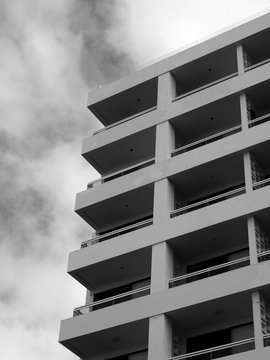 corner view of concrete generic white modern apartment building with balconies and railings