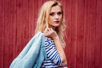 Fototapeta premium Gorgeous blonde woman dressed in casual style sits on a wooden bench