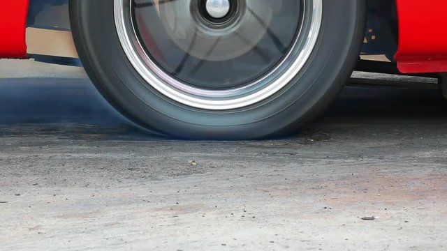 Drag racing car burns rubber off its tires in preparation for the race.