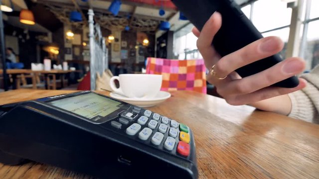 Smartphone payment. Female hand pay using nfc system and contactless card.